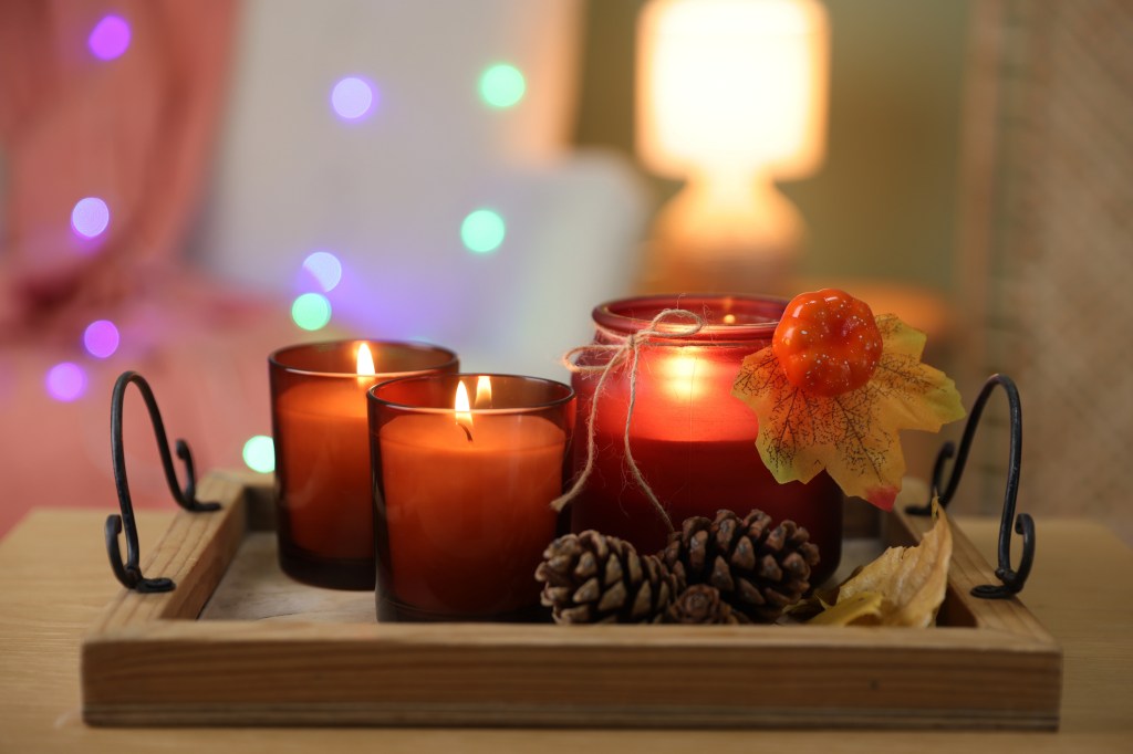 Burning candles and autumn decor on wooden table indoors