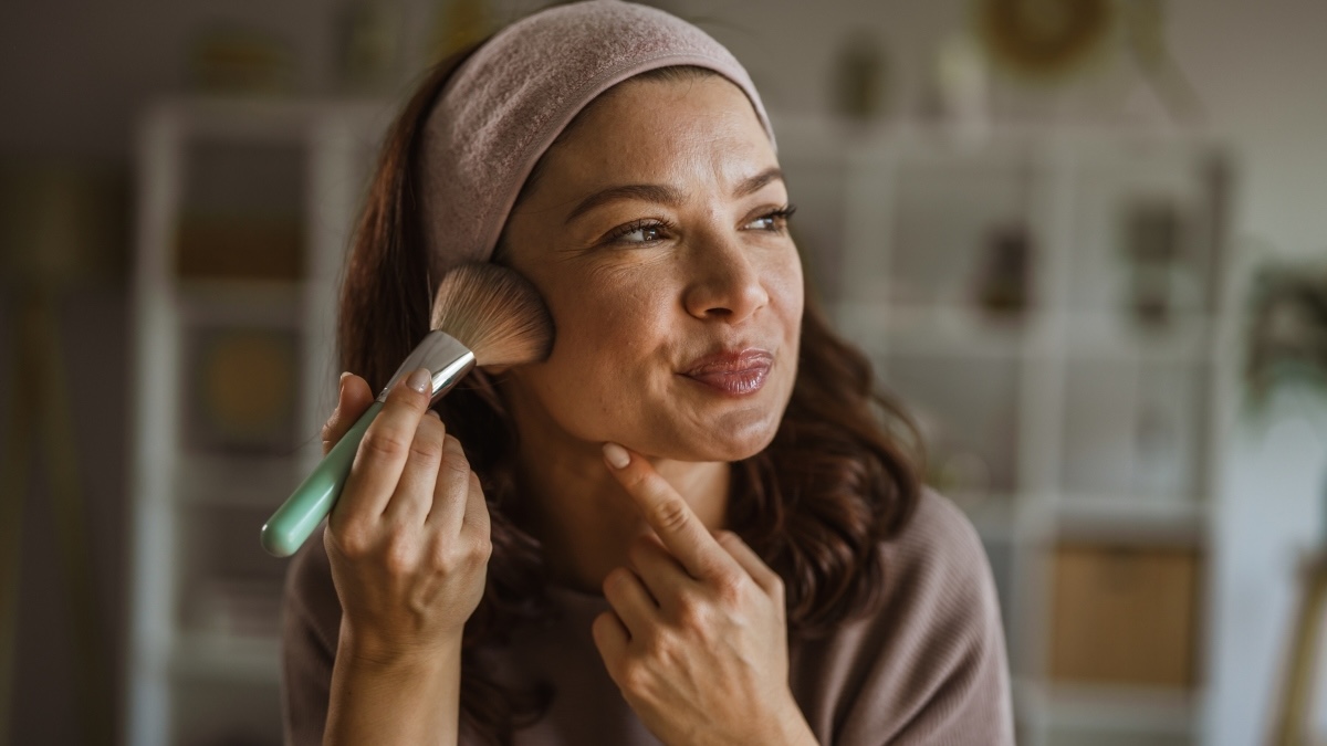 A woman applying her makeup to avoid it melting during hot flashes