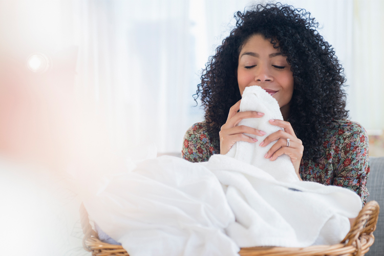Young woman smelling her freshly cleaned white towels.