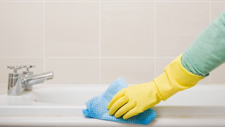 how to clean a bathtub: Person cleaning bath