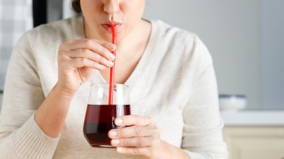 Close-up of a woman drinking pomegranate juice to lower her blood pressure quickly